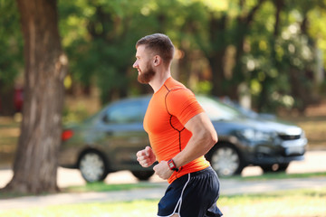 Young man running in park on sunny day