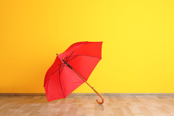 Beautiful open umbrella on floor near color wall with space for design