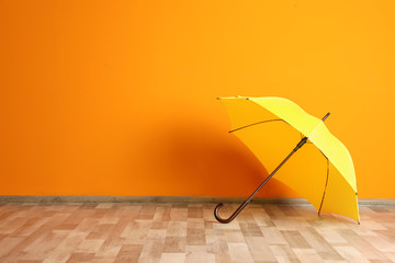 Beautiful open umbrella on floor near color wall with space for design