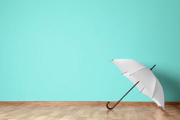 Beautiful open umbrella on floor near color wall with space for design - obrazy, fototapety, plakaty