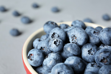 Crockery with juicy and fresh blueberries on color table, closeup