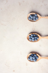 Flat lay composition with spoons and juicy blueberries on color table. Space for text