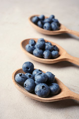 Wooden spoons and juicy blueberries on color table