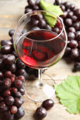 Glass of red wine and fresh ripe juicy grapes on table