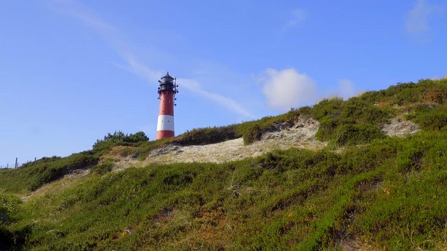 Wundersch&ouml;ner Leuchtturm H&ouml;rnum Sylt mit D&uuml;nen Landschaft  und blauen Himmel
