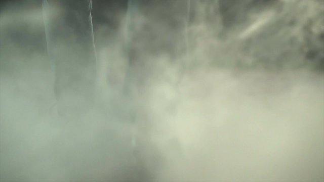 The legs of a man walking near a cloud of smoke. evening night time, slow motion