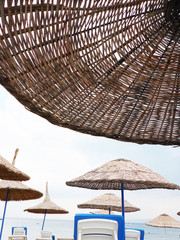 White beach chairs and wicker umbrellas at the beach in Sarimsakli, Turkey
