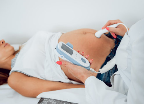 A gynecologist examines a pregnant woman. Fetal doppler heart auscultation. Patient at doctor office.