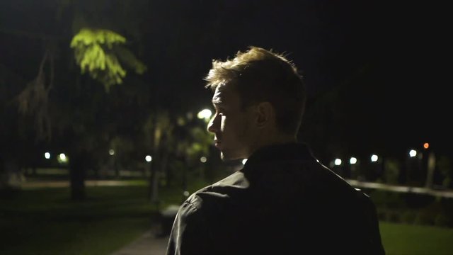 The handsome man walking in the night park. slow motion