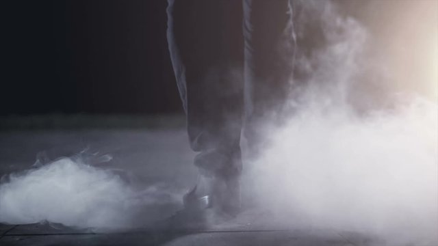 The male legs going near a smoke. evening night time, slow motion