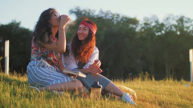 Two girls are discussing an interesting book and drinking coffee