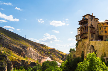 Obraz premium Sunny scene of the Hanged Houses (Casas Colgadas) and the mountains in the city of Cuenca, Spain. Touristic houses built on the rocks of a cliff.