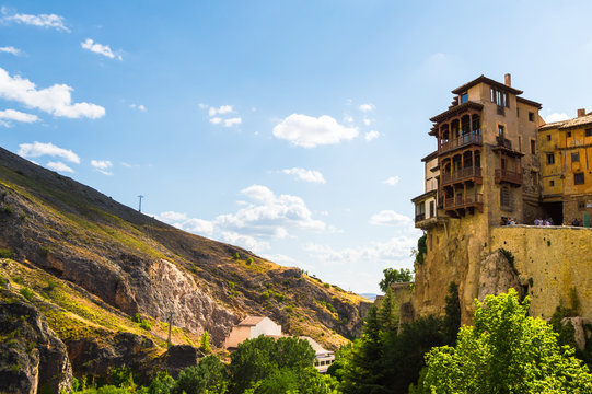 Sunny scene of the Hanged Houses (Casas Colgadas) and the mountains in the city of Cuenca, Spain. Touristic houses built on the rocks of a cliff.