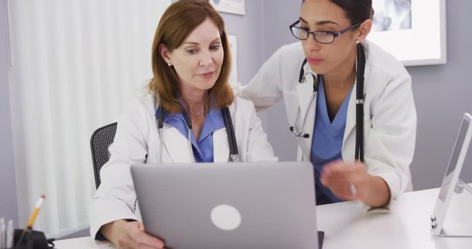 Two medical doctors using notebook computer to discuss patients healh condition