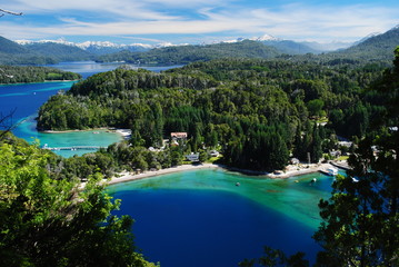 Beautiful incredible view of a blue, green and turquoise bay of a lake, surrounded by a forest and with the Andes in the horizon, Villa la Angostura, Argentina