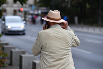 A stylish dressed old man is phoning in Berlin Germany