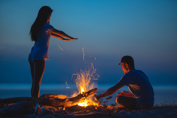The man and a woman resting near the fire. evening night time