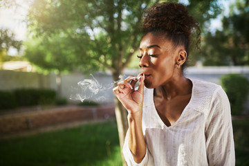 happy african american woman smoking marijuana joint in back yard © Joshua Resnick
