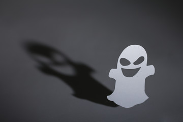 Halloween background concept. Funny ghost and graphic shade, hard light on dark table.