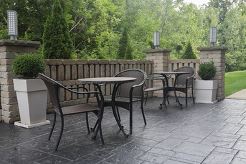 Two Tables and Chairs on hotel patio in the morning sunlight with greenery in the background