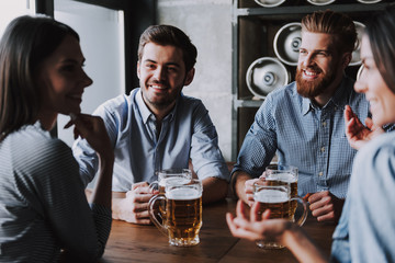 Company Friends Sitting and Drinking Beer in Pub