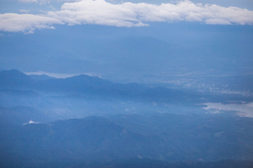 Background, high angle from the passenger plane. You can see the scenery by the distance (mountains, rivers, sky, fog, houses), the photos may be blurred during the flight.