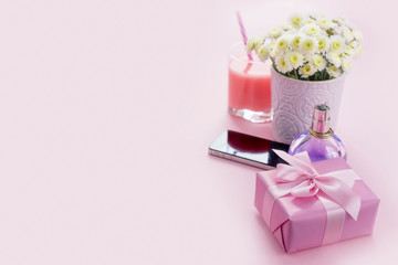 Composition flat lay gift to a woman Modern gadget mobile phone glass cocktail perfume bouquet of flowers Preparing for the holiday surprise gift box pink background