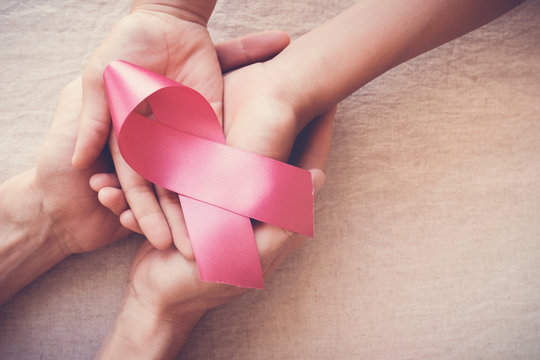 hands holding pink ribbon, breast cancer awareness, October pink concept