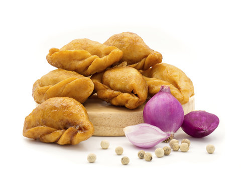 Packshot close up view of "Pan Klib" traditional mini Thai puff dessert stuffed material with fish, curry, shallot, pepper seasoned sugar and salt on wood plate isolate on white background