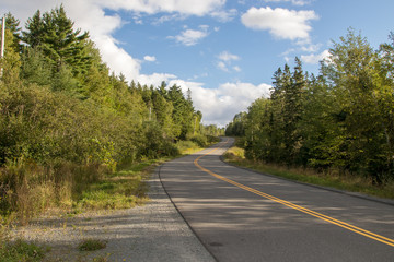 Roadway uphill with clouds in sky, summer, no people, no cars, peaceful.