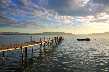 View of  wooden pier on the amazing idyllic of the fishing village and tropical ocean in the sunrise, Gulf of Thailand