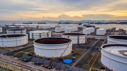 Natural gas storage tanks and oil tanks in oil refinery plant at industrial zone at sunset.