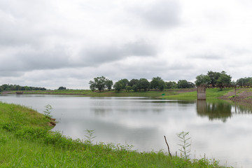 wild river and green grass in summer cloudy landscape.