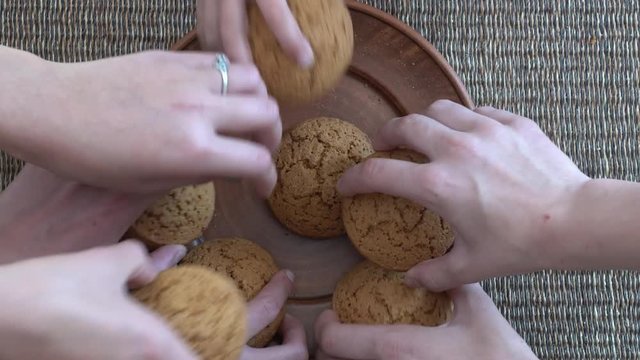 Plate full of oatmeal cookies being snatched up by four hungry children girls.  Close up, top view, macro