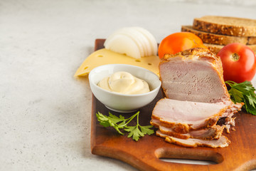 Ingredients for ham and cheese sandwiches on a wooden board, white background.