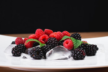 Large blackberries. Blackberries in a white plate on a wooden table.