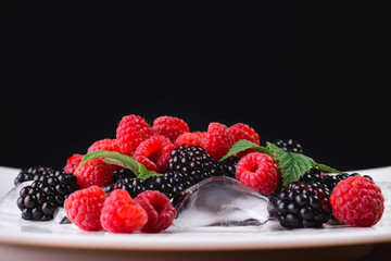 Large blackberries. Blackberries in a white plate on a wooden table.