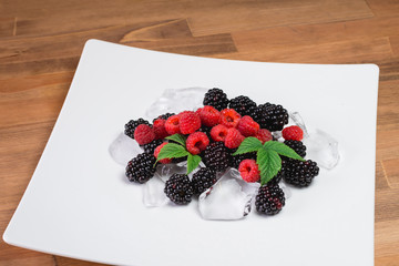 Large blackberries. Blackberries in a white plate on a wooden table.