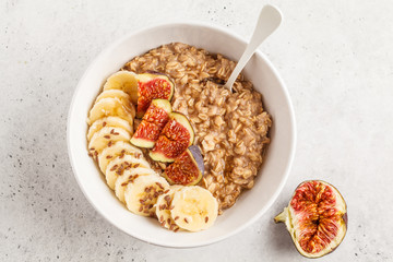 Autumn oatmeal with banana, fig and flax seed. White background, top view