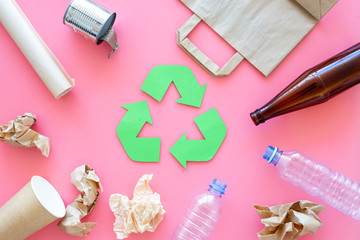 Recycling. Green recycle eco symbol. Recycled arrows sign near matherials for recycle and reuse on pink background top view