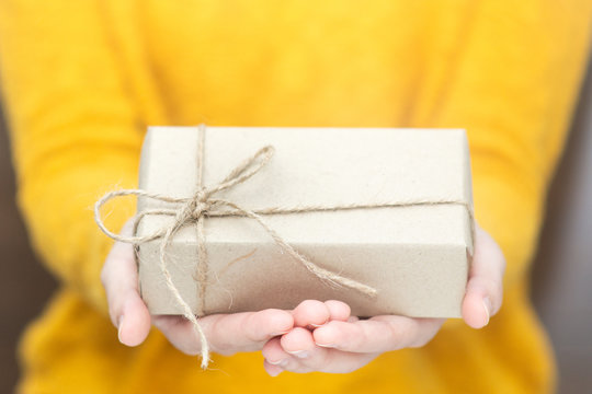 Young woman in yellow swether holding gift box for spacial event.