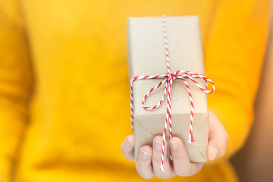 Young woman in yellow swether holding gift box for spacial event.