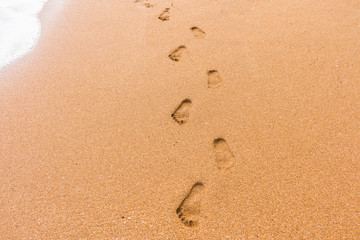 Fototapeta na wymiar Footprints in the sand with sea background