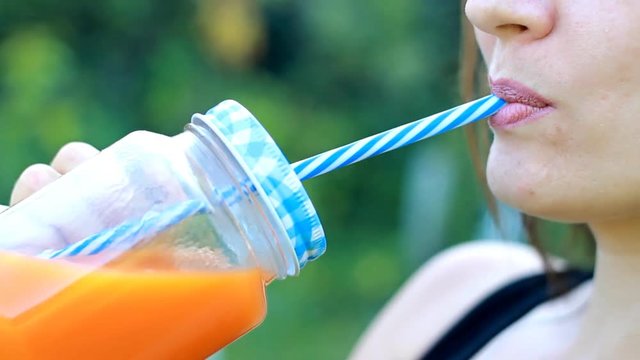 Woman drinks smoothies or orange fresh outdoors.