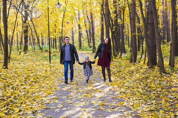 Fototapeta premium Family, fall, people concept - mixed race young family walking in park on in autumn day