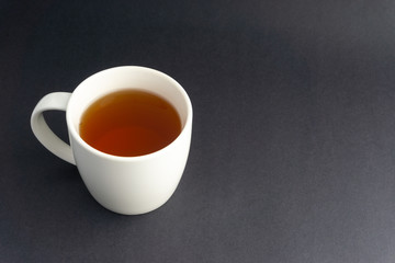 Cup of tea on dark background with selective focus and crop fragment
