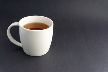 Cup of tea on dark background with selective focus and crop fragment