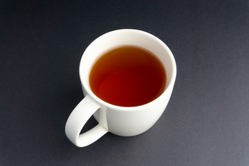 Cup of tea on dark background with selective focus and crop fragment