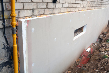 Insulating old  flat house foundation with white polystyrene - obrazy, fototapety, plakaty