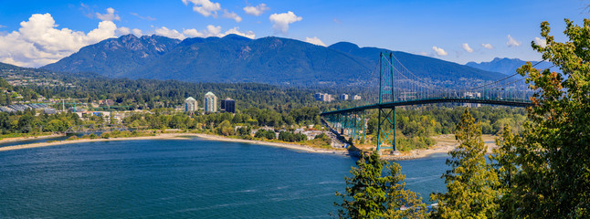 Lions Gate or First Narrows Bridge in Stanley Park Vancouver Canada with North Vancouver and mountains in the background - obrazy, fototapety, plakaty